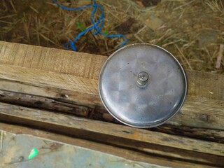 The metal pot lid is placed on a block of wood, the glass lid looks like it is made of metal.