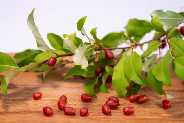 Goji berries branch with green leaves on wooden board, A branch with fresh goji berries and green...