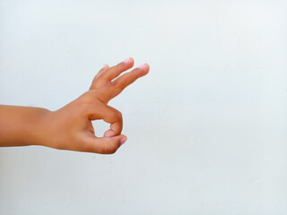 Asian kid's hand showing an OK gesture on white background.