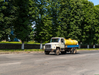 Obraz premium A yellow and blue truck driving down a street next to trees