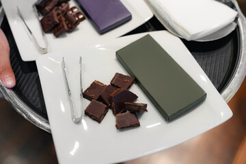 Chocolate tasting setup with assorted bars and tongs on serving tray. Chocolate bars mockup.