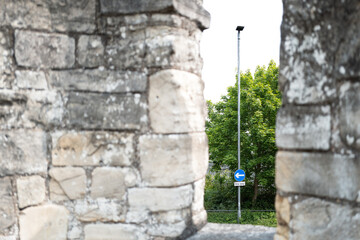 Shallow focus of a standard One Way traffic sign seen through the ramparts of the famous roman,...