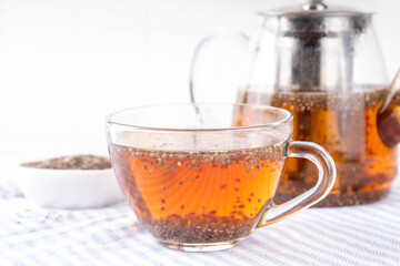 Chia seeds tea, trendy healthy chia infused drink, alternative natural energy source, diet weight-loss drink, in teapot and tea cup, copy space