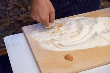 A person is spreading a fine layer of flour on a cutting board