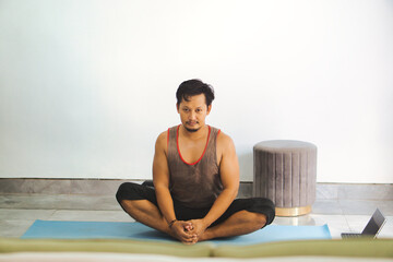 Man Practicing Yoga Pose Indoors on a Mat in Simple Setting