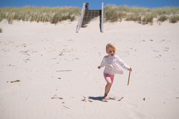 Little Girl Playing Alone in the Sand on the Beach