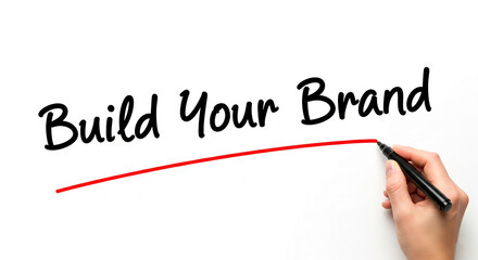 Hand writing Build Your Brand phrase on white background, underlined in red, showcasing business growth and branding concept