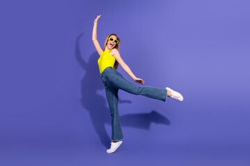 Playful young woman in vibrant outfit posing joyfully in front of purple background showcasing...