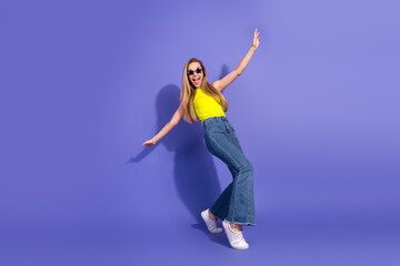 Young cheerful woman in stylish clothing posing on a violet background, expressing happiness and...