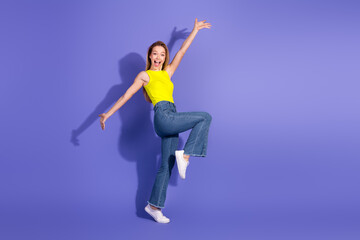 Cheerful young woman jumping with joy against a vibrant purple backdrop