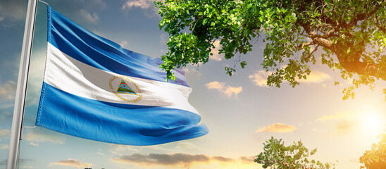 Nicaragua national flag waving in the sky behind the tree. The flag blow in beautiful sunlight....