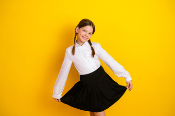 Stylish schoolgirl wearing a formal uniform posing against a vibrant yellow background, showcasing her charismatic charm.