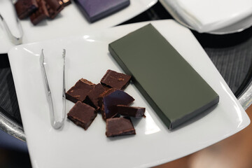 Chocolate tasting setup with assorted bars and tongs on serving tray. Chocolate bars mockup.