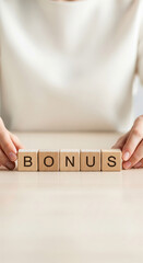 Wooden blocks spelling "BONUS" on a table, hands arranging them, symbolizing reward, achievement, or extra payment