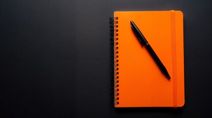 Creative Workspace: A vibrant orange notebook lies open beside a sleek black pen, inviting productivity and the free flow of ideas, a visual representation of the creative process.