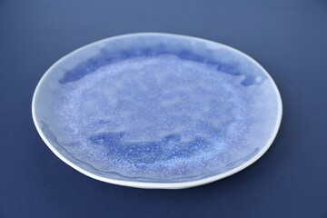 One empty plate on blue background, closeup
