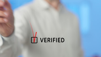 Businessman drawing a red check mark in a checkbox with the word verified next to it, symbolizing...
