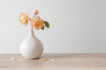 yellow roses in ceramic vase on wooden table