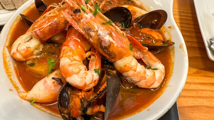 Savory seafood medley in a bubbling cauldron stew, perfect for La Tomatina or unconventional Ocean Day feasts