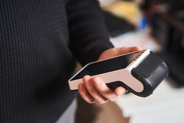 Bank terminal for contactless payment. Acquiring. Young man holds a terminal in his hands.