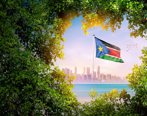 South Sudan flag wavering against modern skyline. Sudan national flag for independence day.