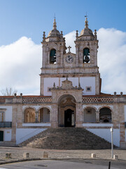 Front view of Historic baroque church with twin bell towers, clock and steps, captured in daylight.