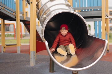 Child enjoying a playful moment sliding down a playground slide at a community park during a sunny afternoon
