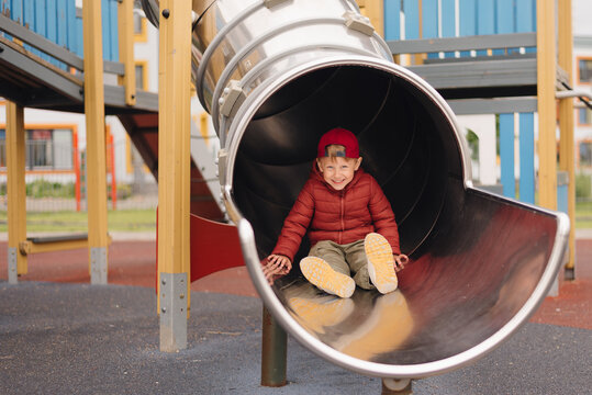 Child enjoying a playful moment sliding down a playground slide at a community park during a sunny afternoon