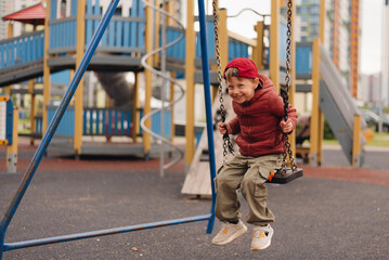 Obraz premium Child enjoys swinging on playground in urban area during sunny day, showcasing happiness and playfulness