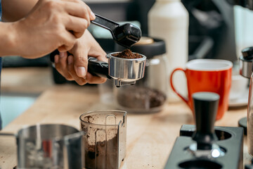 A young Asian male barista, dressed in a striped apron, skillfully creates beautiful latte art in a cozy, modern cafe, professional coffee equipment and takeaway cups.