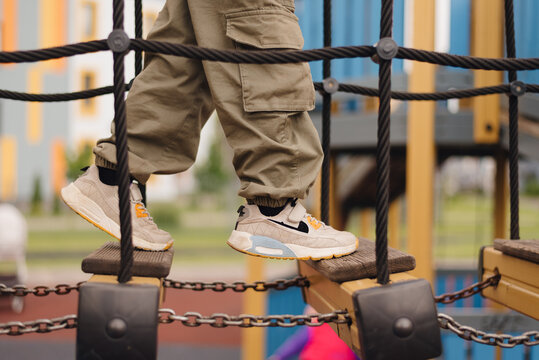 Child navigating a playground bridge while wearing stylish athletic shoes during a sunny day