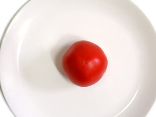 One red tomato on a white plate