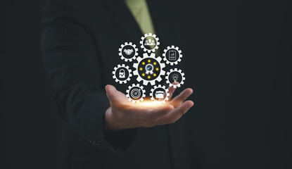 Businessman presenting interconnected gears with business strategy icons, symbolizing collaboration, innovation, and teamwork driving company growth, digital workflow, and operational efficiency.