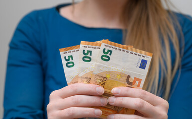 A woman holds euro banknotes in her hands, 150 euros