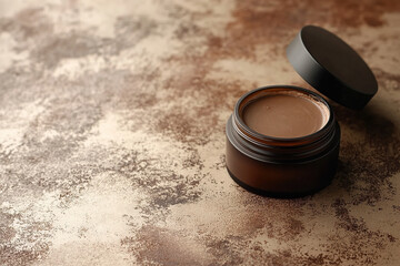 Open jar of lip balm on textured background of trendy mocha 2025 color. The concept of natural cosmetics.