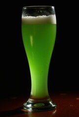 Emerald Elixir: A tall, elegant glass presents a vibrant green liquid, topped with a frothy white head, evoking a sense of refreshing indulgence, captured against a warm, dark background.