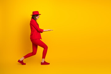 Stylish young woman in a vibrant red suit and matching hat posing against a bright yellow background showcasing energy