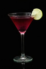 Cosmopolitan Cocktail: A vibrant Cosmopolitan cocktail, garnished with a lime wedge, sits elegantly in a martini glass against a dramatic black background.