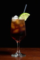 Refreshing Summer Sip: An inviting cocktail featuring a perfect blend of refreshing iced drink with lime, ice and a straw, served in an elegant glass against a dark backdrop.