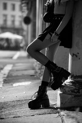 Closeup of legs of gothic girl wearing sexy stockings and black boots standing in the street