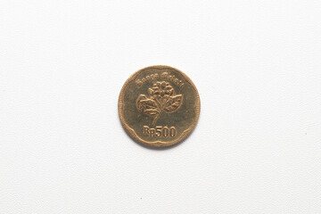 A single Indonesian 500 Rupiah coin, displaying a jasmine flower and "Rp 500," rests on white surface