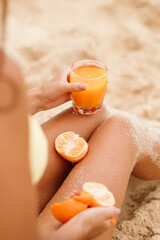 Hands holding a fresh orange juice and fruit pieces, against sun-kissed skin. Bright, tactile and summery.