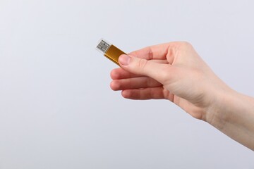 Man with modern flash drive on light grey background, closeup. Space for text