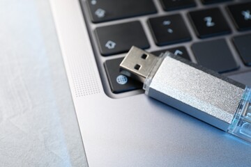Flash drive and laptop on light grey table, closeup