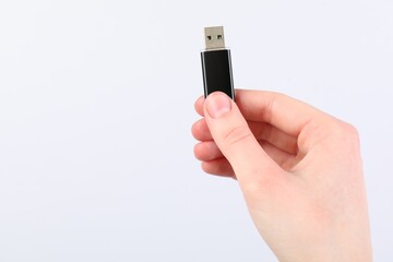 Man with modern flash drive on light grey background, closeup. Space for text
