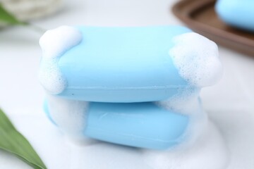 Soap bars with foam on white table, closeup