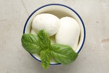 Tasty mozzarella cheese and basil on light table, top view