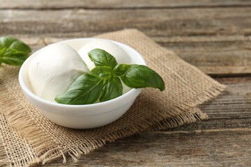 Tasty mozzarella cheese and basil on wooden table, closeup. Space for text