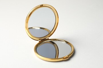 Open pocket mirror on light grey background, closeup