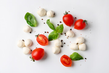Tasty mozzarella balls, tomatoes, peppercorns and basil on white background, flat lay